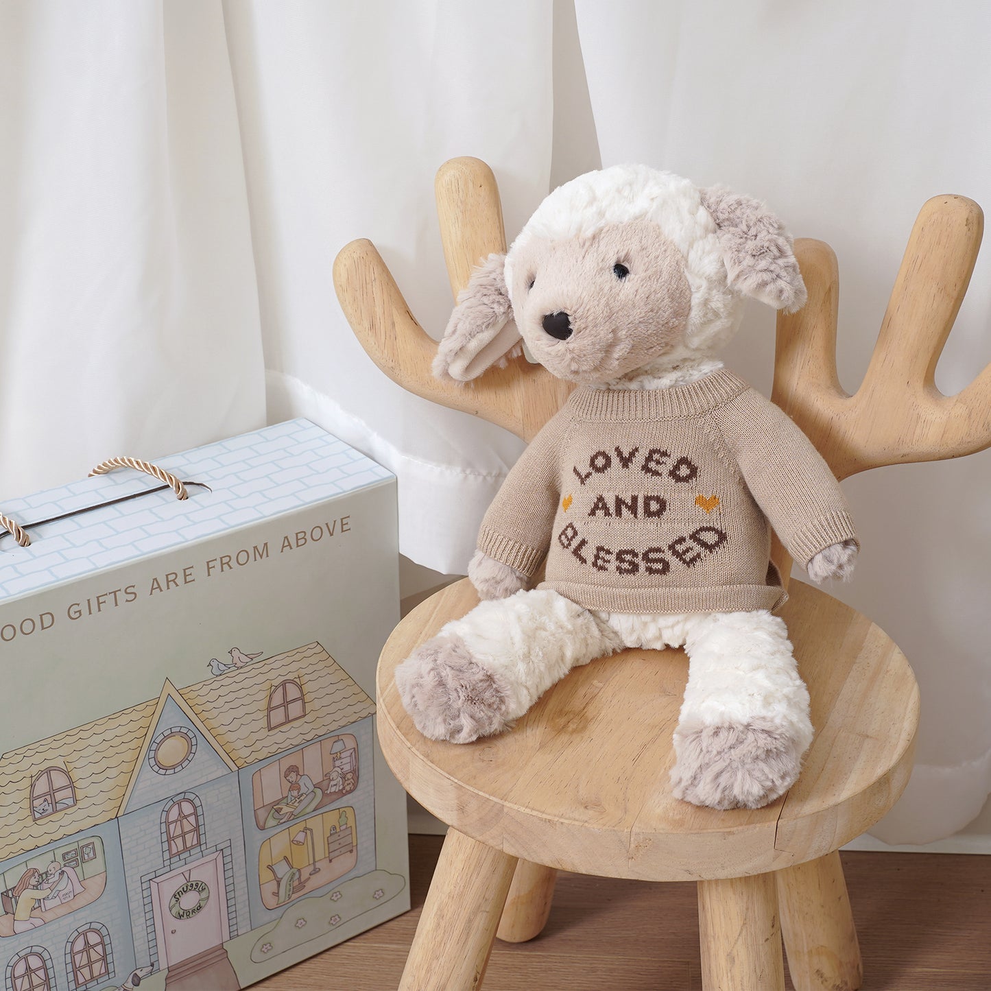 Little Lamb plush animal toy for baby gift, wearing a sweater, on a wooden stool next to a gift box.