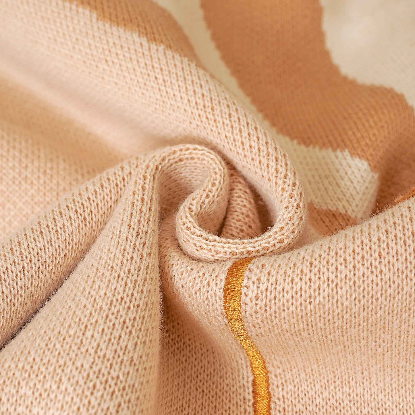 Close-up of a soft knitted baby blanket in tan and cream, with embroidered gold Philippians 4:13 verse details.