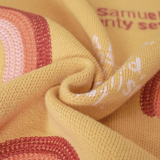 Close-up of a mustard yellow knit Christian baby blanket, with pink & red rainbow and '1 Samuel 1:27' text.