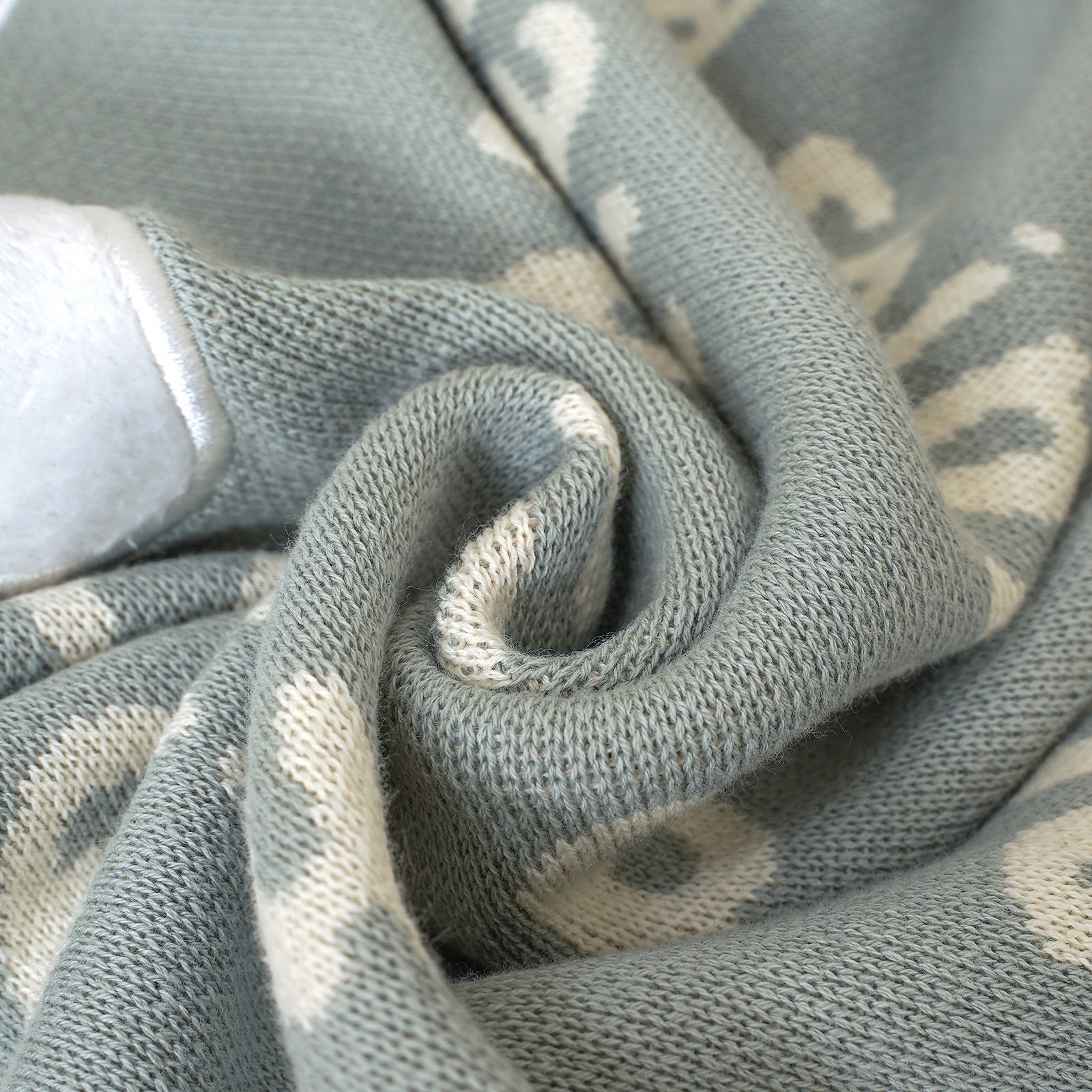 Close-up of a soft green knitted baby blanket, with cream words "YOU ARE THE LIGHT Matthew 5:14" detail.