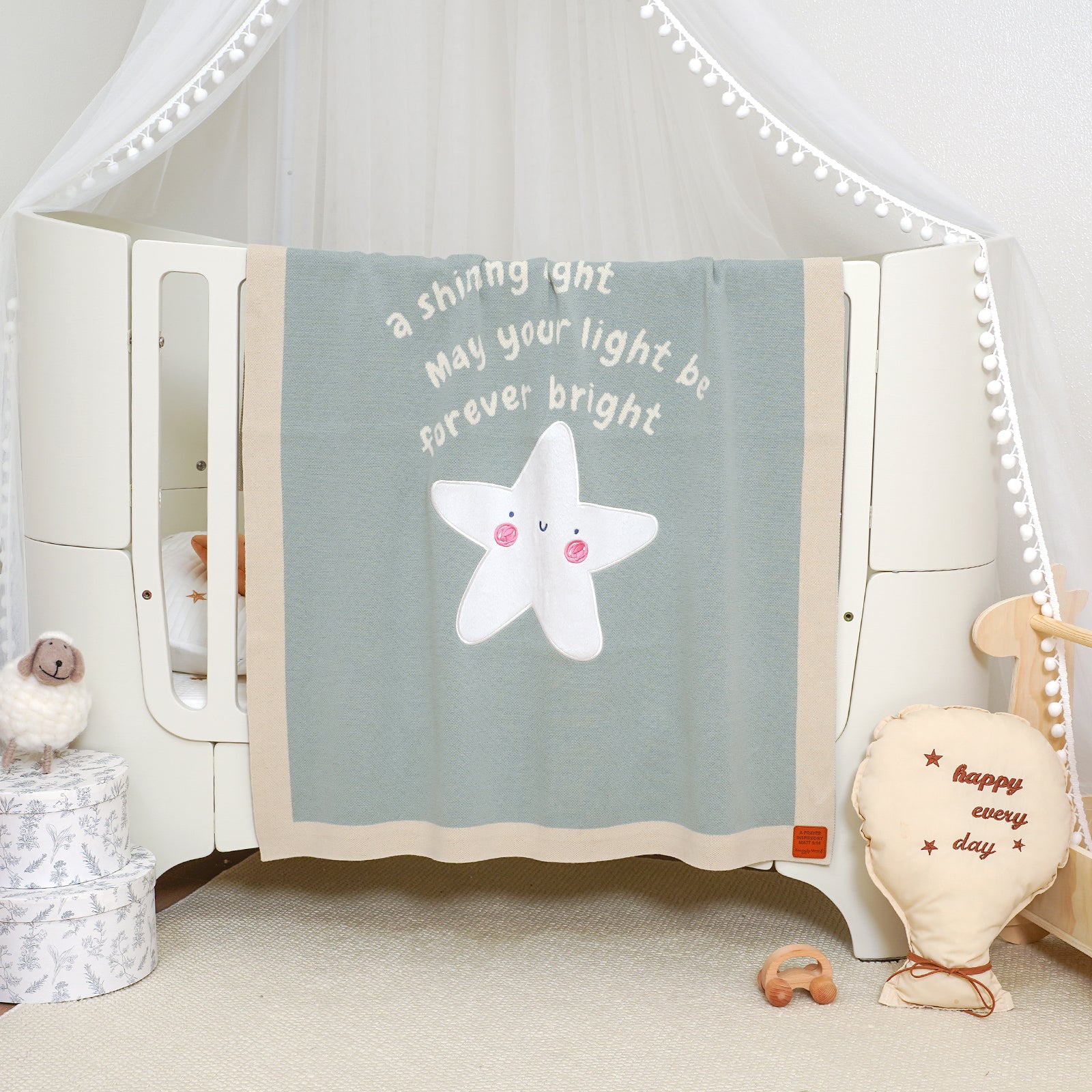 Matthew 5:14 Scripture baby blanket with 'May your light be forever bright' text and star, draped on a crib.