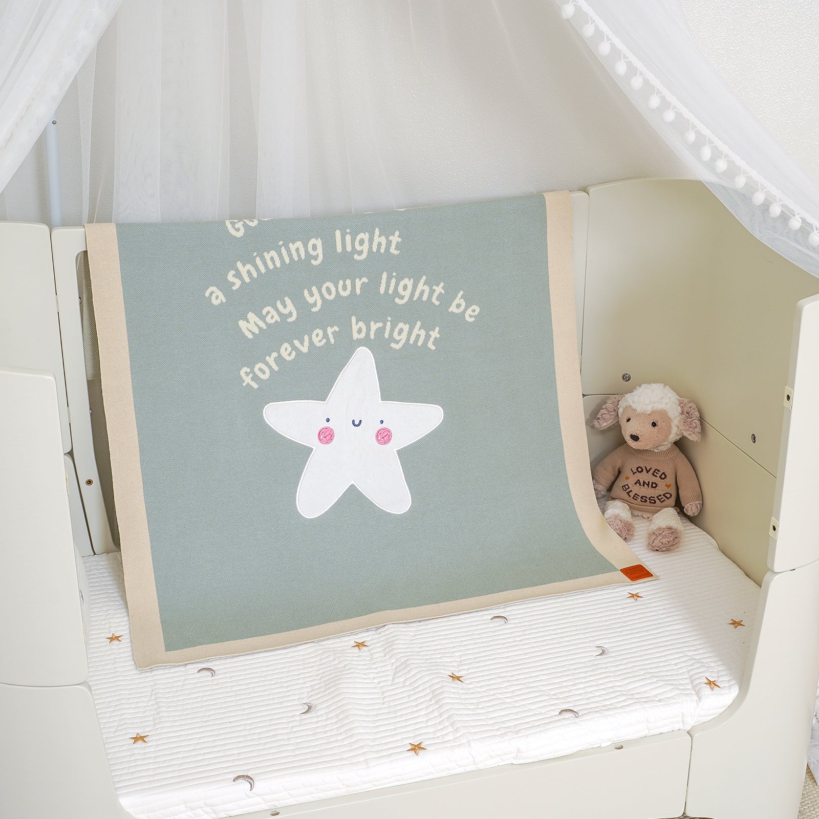 Matthew 5:14 baby blanket with 'You are a shining light' quote & star, draped over a crib with a stuffed animal.